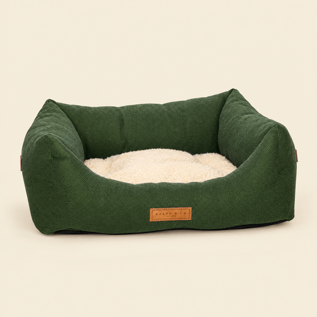 The Richmond green bolster bed by Ralph & Co on a cream background