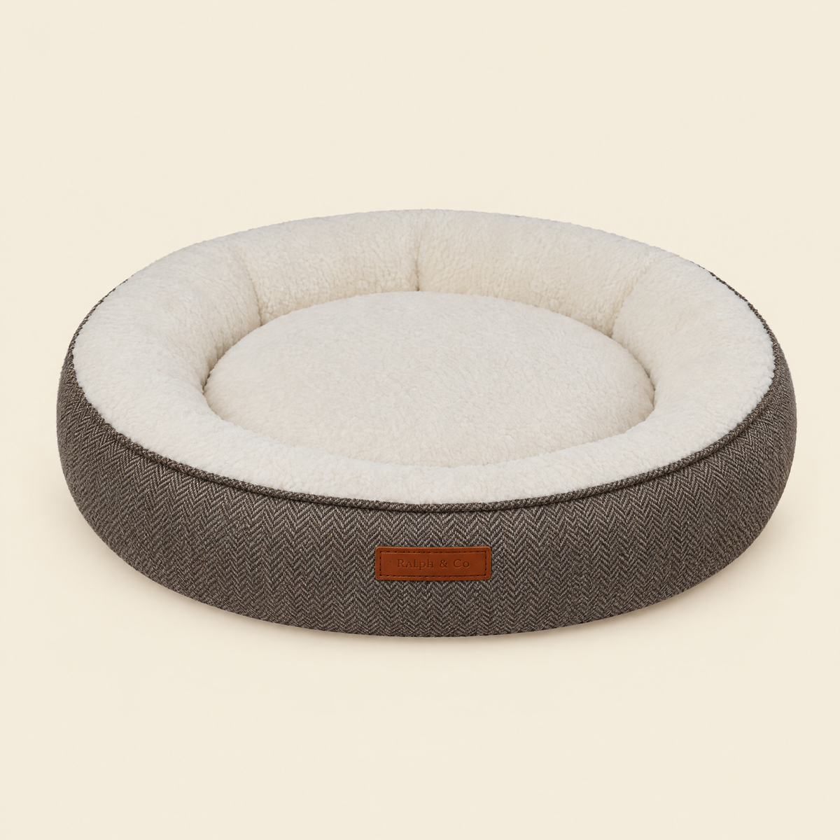 The Lincoln tweed calming donut bed by Ralph & Co on a cream background