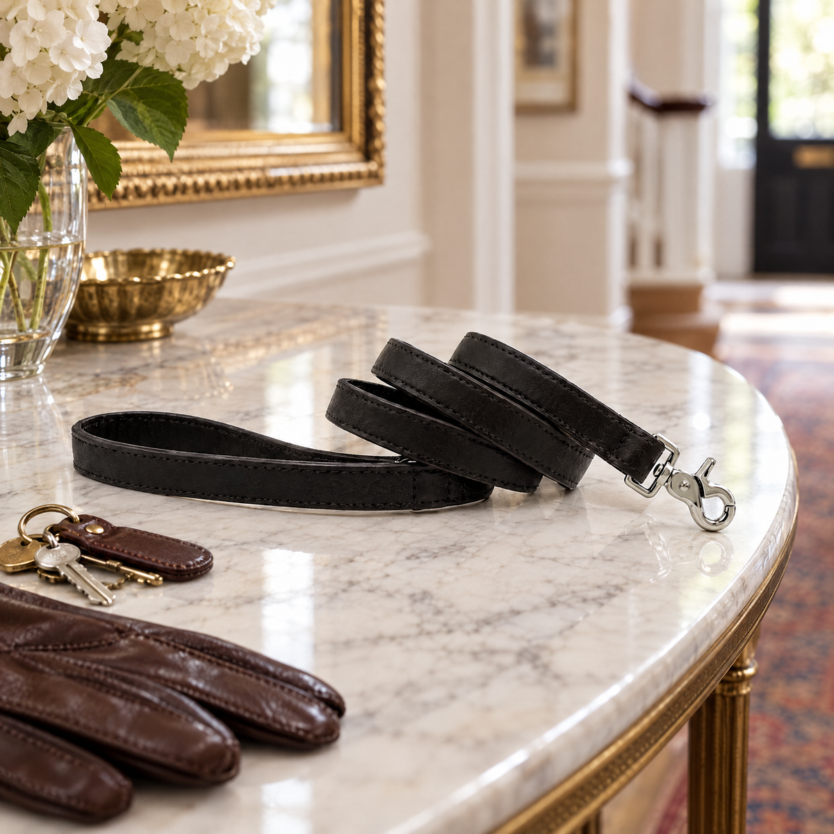 The Black Vegan Leather Dog Lead laid on a marble hall console with keys and leather gloves