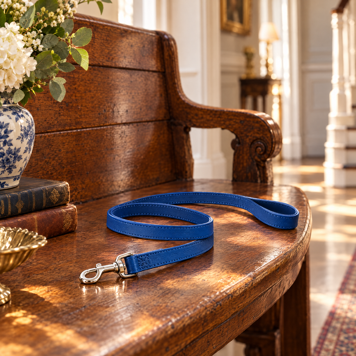 The Royal Blue Vegan Leather Dog Lead by Ralph & Co curled on an antique oak hall bench in a sunlit Georgian hallway