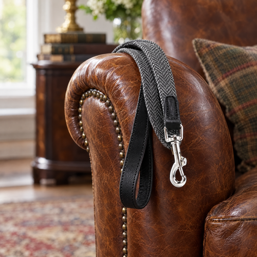 The Balmoral Grey Herringbone & Leather Dog Lead by Ralph & Co draped over the arm of a leather club chair