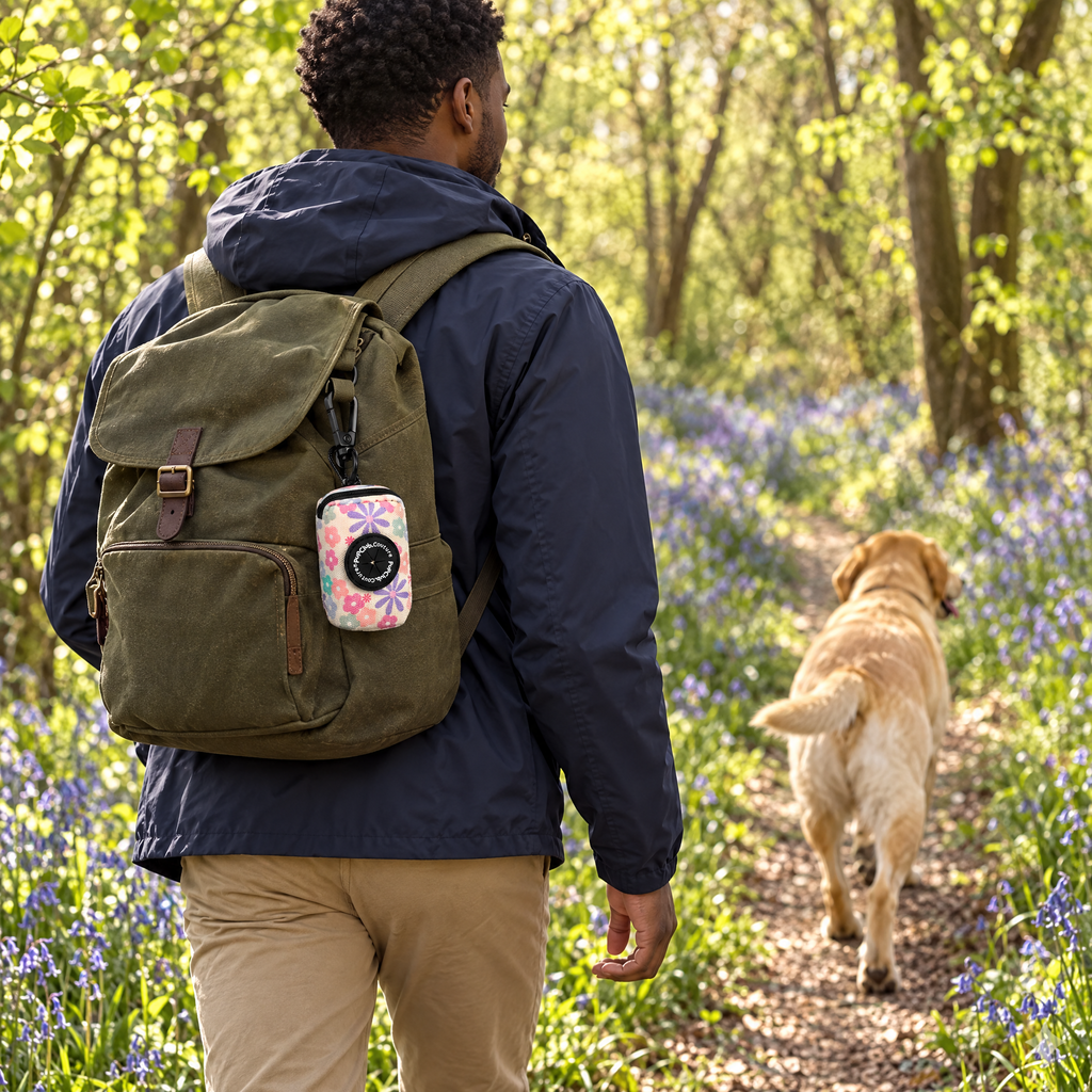 Pretty Petals poo bag holder clipped to a backpack on a dog walk