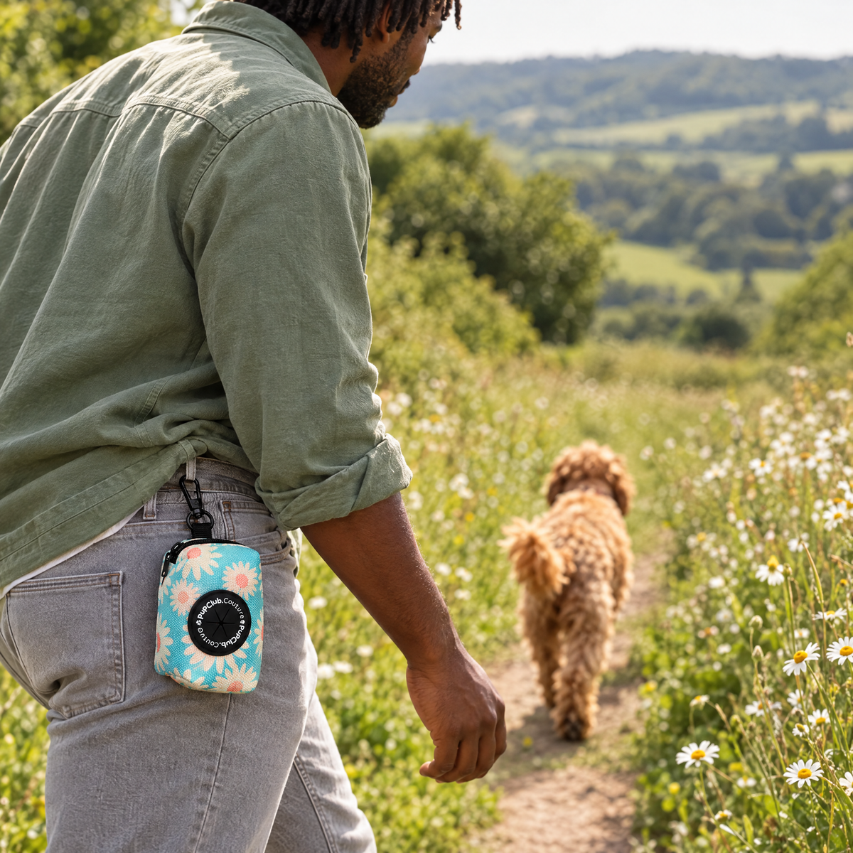 Pastel Daisy poo bag holder clipped to a belt on a dog walk