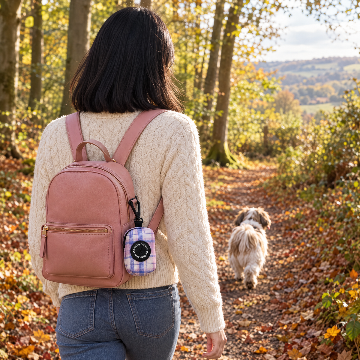 Pink Tartan poo bag holder clipped to a backpack on a dog walk