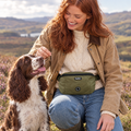 Woman giving her dog a treat from the Khaki Green dog walking bum bag by PupClub Couture